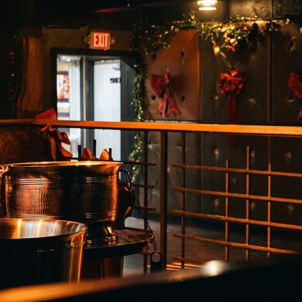 Dark, festive bar interior with metal ice buckets, leather seating, and holiday decorations.